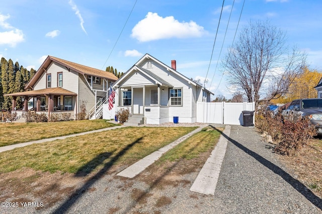 bungalow-style house featuring driveway, covered porch, a gate, fence, and a front lawn