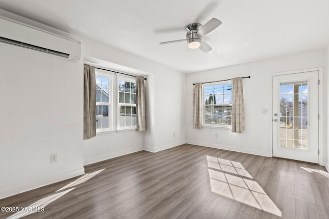 unfurnished room with baseboards, wood finished floors, and a wall mounted air conditioner