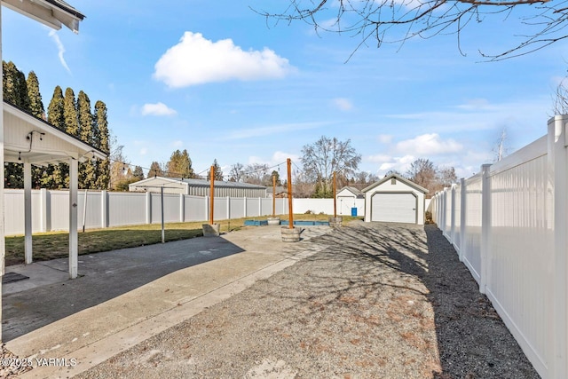 view of yard featuring a patio area, a garage, a fenced backyard, an outdoor structure, and driveway