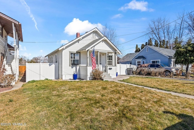 bungalow-style house featuring fence, a chimney, and a front lawn