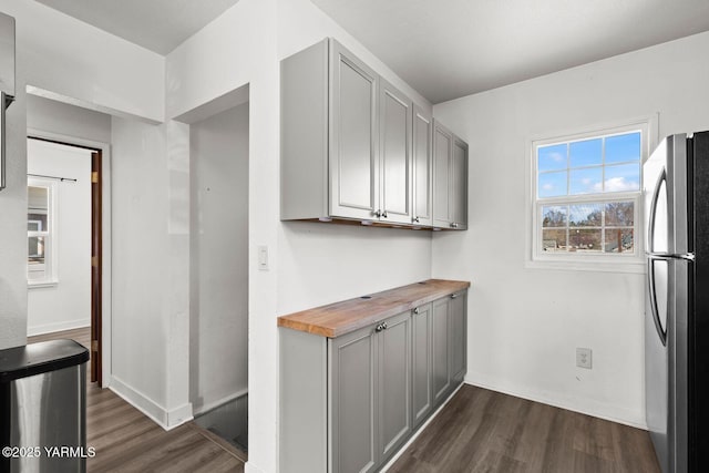 kitchen featuring baseboards, dark wood-type flooring, freestanding refrigerator, and gray cabinetry