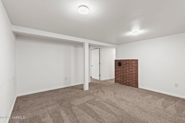 finished basement featuring a textured ceiling, carpet floors, and baseboards