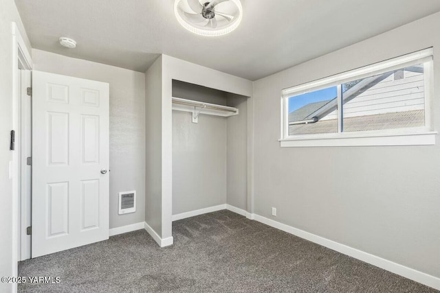 unfurnished bedroom featuring dark colored carpet, a closet, visible vents, and baseboards