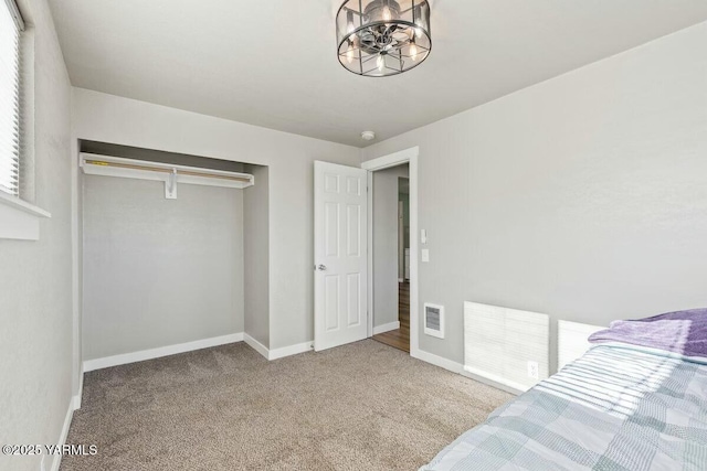 carpeted bedroom featuring baseboards, visible vents, and a closet