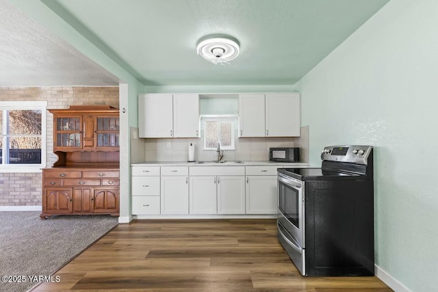 kitchen featuring black microwave, light countertops, white cabinets, and stainless steel electric stove