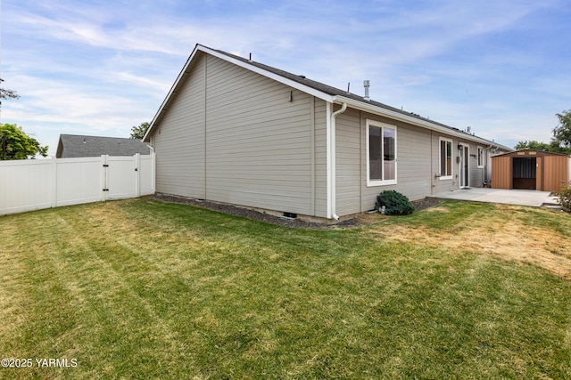 view of home's exterior with a storage shed, a lawn, a gate, fence, and a patio area