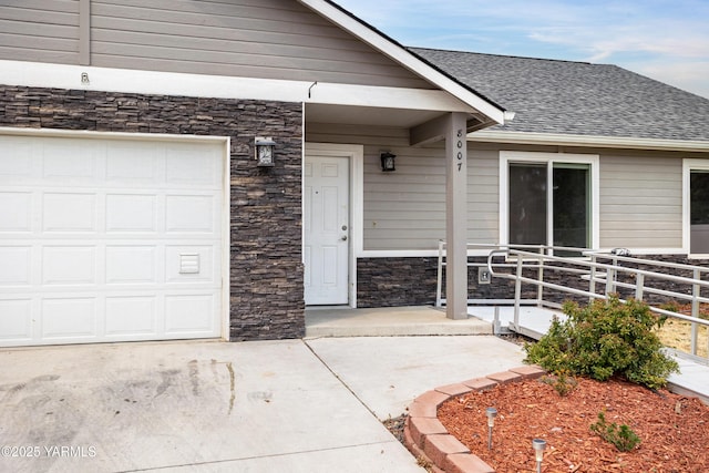 property entrance with a garage, stone siding, a shingled roof, and driveway