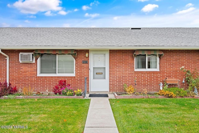 property entrance featuring brick siding, a lawn, and roof with shingles