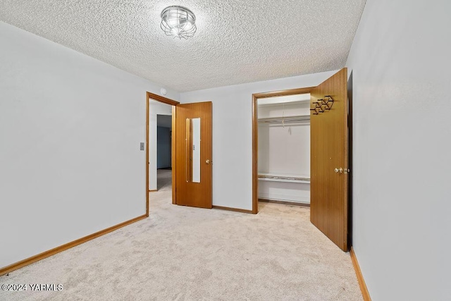 unfurnished bedroom featuring a closet, light colored carpet, a textured ceiling, and baseboards