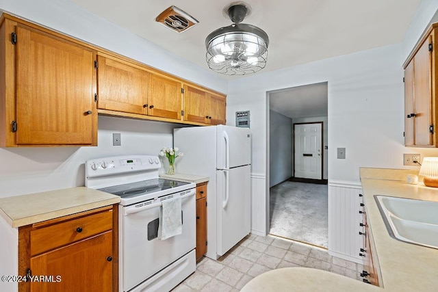 kitchen featuring white appliances, light countertops, a sink, and brown cabinetry