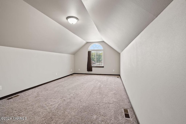 bonus room with carpet, visible vents, vaulted ceiling, and baseboards