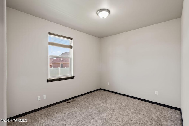 empty room featuring carpet, visible vents, and baseboards