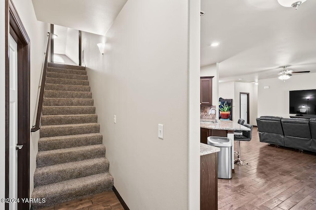 stairs featuring ceiling fan and wood finished floors