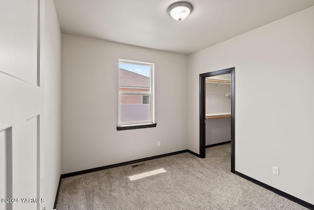 unfurnished bedroom featuring carpet flooring, visible vents, baseboards, a spacious closet, and a closet