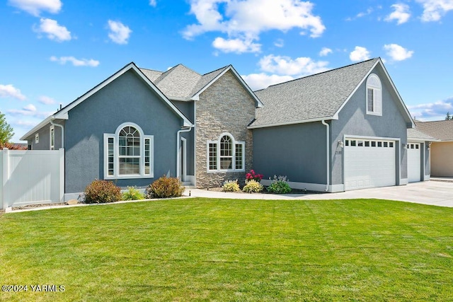 view of front of home with fence, stone siding, driveway, stucco siding, and a front lawn