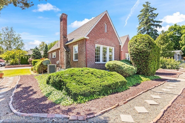 2102 Tieton Dr, Yakima, WA 98902 - view of side of home with a chimney, brick siding, roof with shingles, and central AC unit