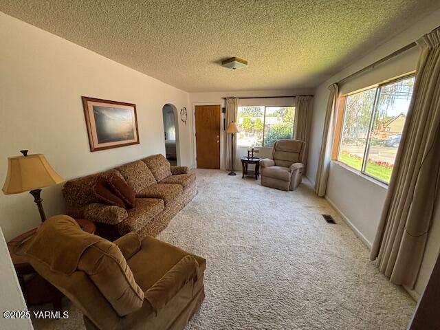 908 W 5th St, Grandview, WA 98930 - living room with arched walkways, a textured ceiling, and light colored carpet