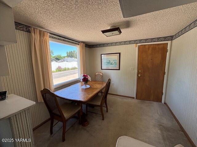 908 W 5th St, Grandview, WA 98930 - dining space featuring a textured ceiling, wallpapered walls, and light colored carpet