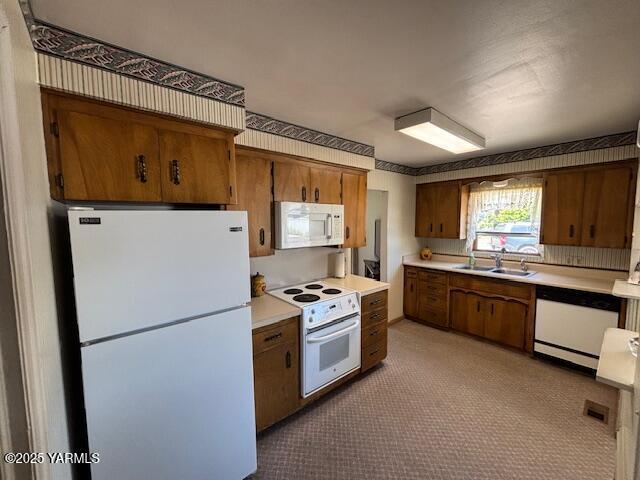 908 W 5th St, Grandview, WA 98930 - kitchen featuring white appliances, brown cabinets, light countertops, and carpet flooring