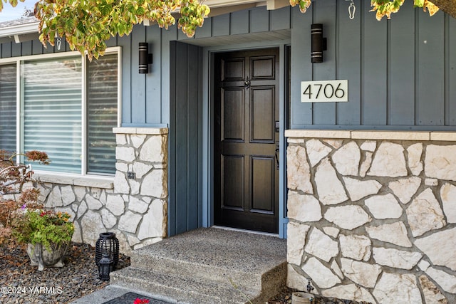 entrance to property featuring stone siding and board and batten siding