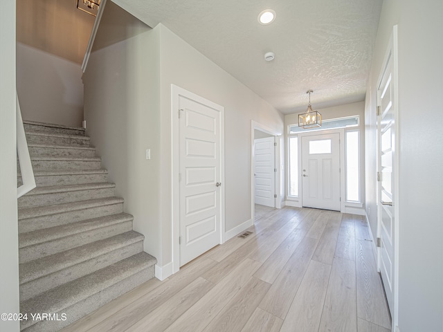 foyer entrance with baseboards, stairway, a textured ceiling, light wood-style floors, and recessed lighting