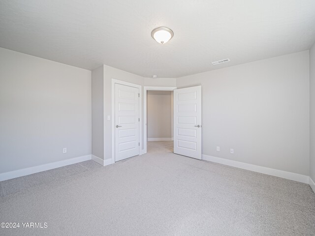 unfurnished bedroom with light colored carpet, visible vents, and baseboards