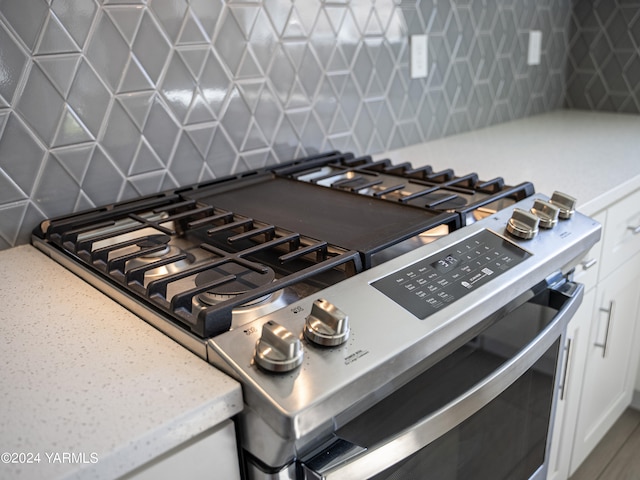 details with light countertops, gas stove, white cabinetry, and decorative backsplash