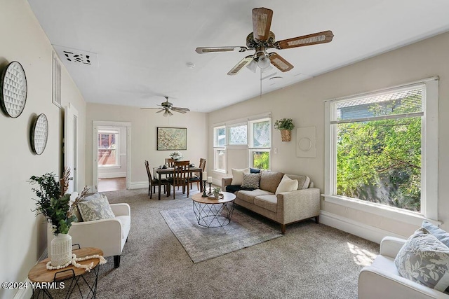 living area featuring carpet floors, visible vents, ceiling fan, and baseboards