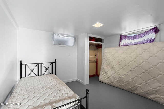 bedroom featuring concrete floors, a closet, and baseboards