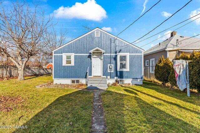 view of front of property featuring entry steps, fence, and a front yard