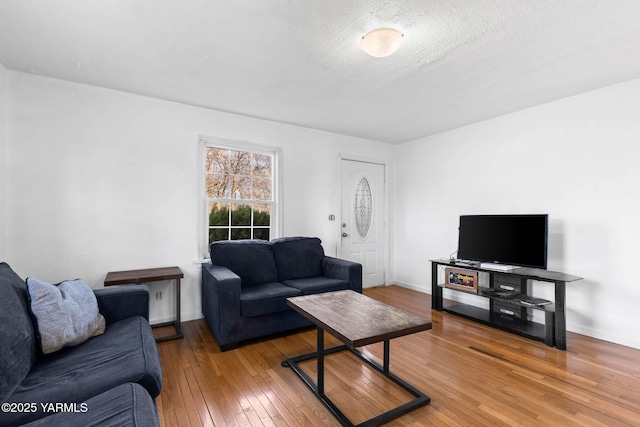 living room with a textured ceiling, wood finished floors, and baseboards