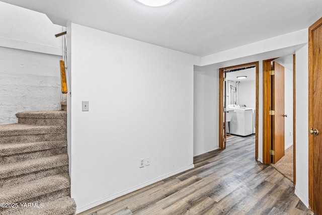 interior space featuring washer / clothes dryer, stairway, wood finished floors, and baseboards