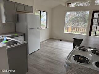 8108 Poplar View Way, Yakima, WA 98908 - kitchen featuring electric range, freestanding refrigerator, healthy amount of natural light, light wood finished floors, and vaulted ceiling