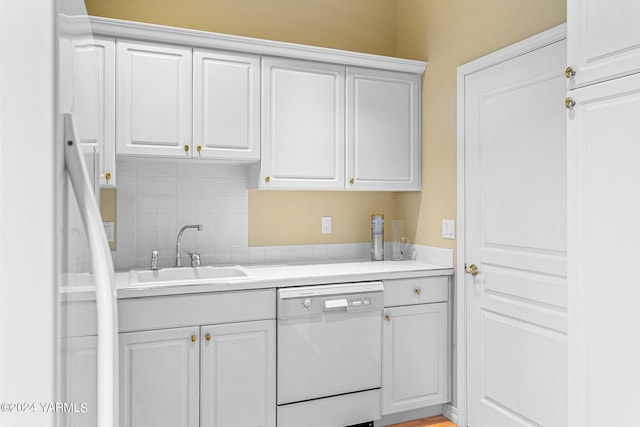 kitchen with white dishwasher, a sink, white cabinetry, light countertops, and backsplash