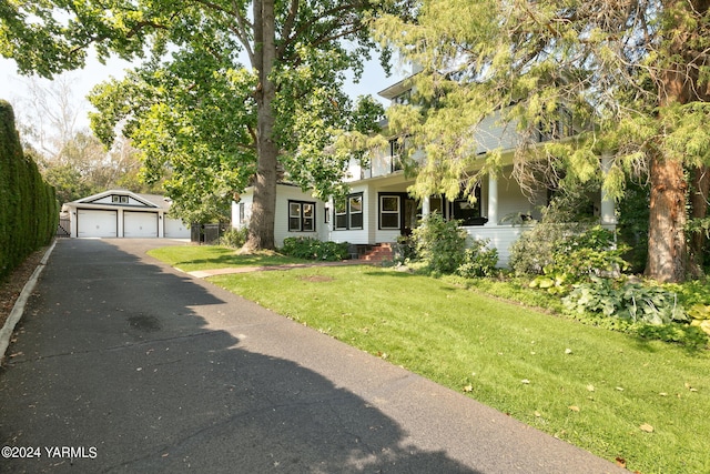 view of front facade featuring an outbuilding, a detached garage, and a front yard