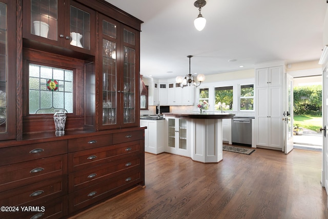 kitchen with stainless steel dishwasher, dark countertops, glass insert cabinets, and decorative light fixtures