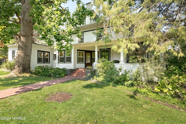 american foursquare style home featuring a front yard and a chimney