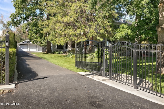 view of gate with a yard, an outdoor structure, and fence