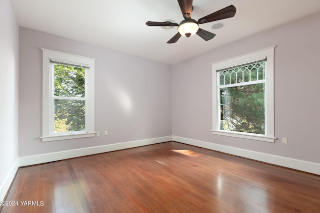 empty room featuring a ceiling fan, baseboards, and wood finished floors