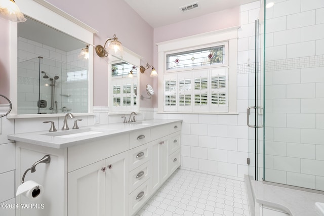 bathroom with double vanity, a stall shower, a sink, and visible vents