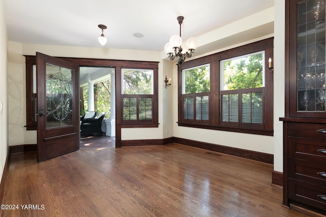 interior space with dark wood-style floors, a notable chandelier, visible vents, and baseboards