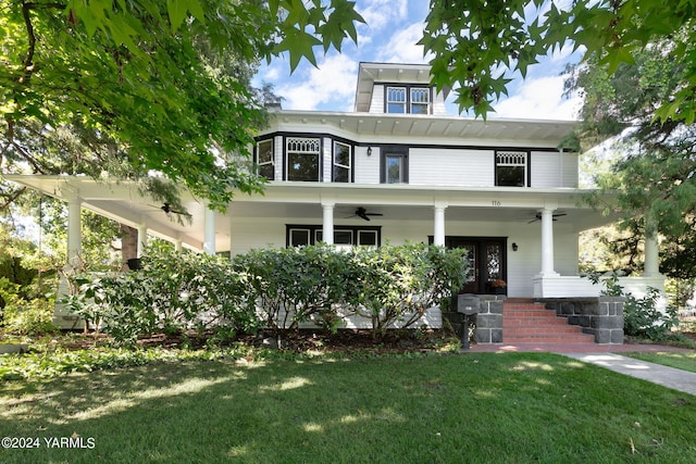 american foursquare style home with a porch, ceiling fan, and a front lawn