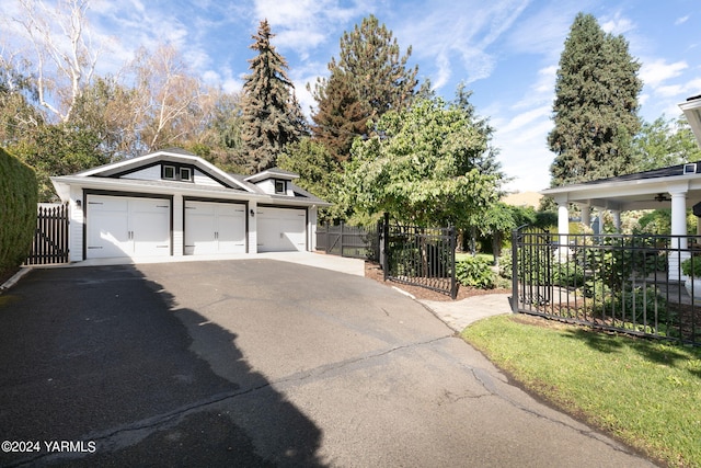 view of front of home featuring an outbuilding, driveway, fence, and a gate