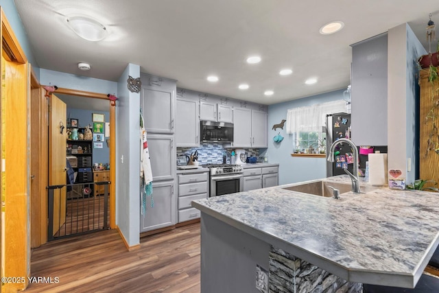 7501 Glacier Way, Yakima, WA 98908 - kitchen featuring appliances with stainless steel finishes, a peninsula, recessed lighting, wood finished floors, and backsplash