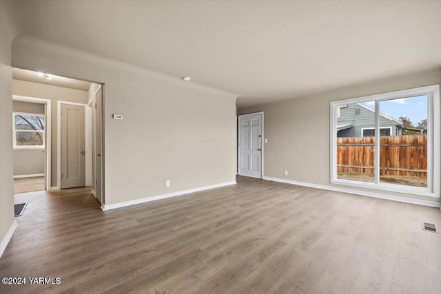 spare room with a wealth of natural light, wood finished floors, visible vents, and baseboards