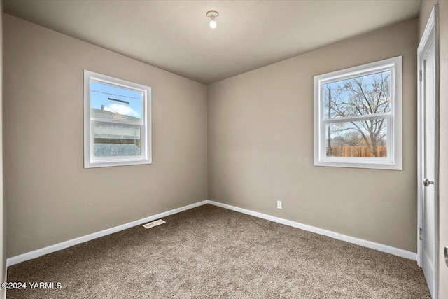 carpeted empty room with visible vents and baseboards