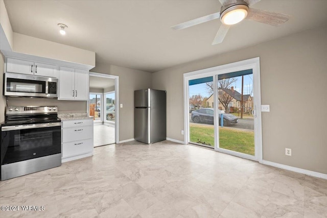 kitchen featuring stainless steel appliances, baseboards, white cabinets, and light stone counters