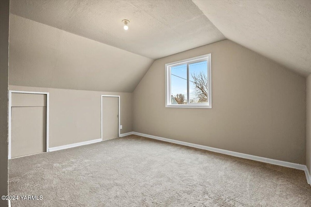 bonus room with a textured ceiling, baseboards, carpet flooring, and lofted ceiling