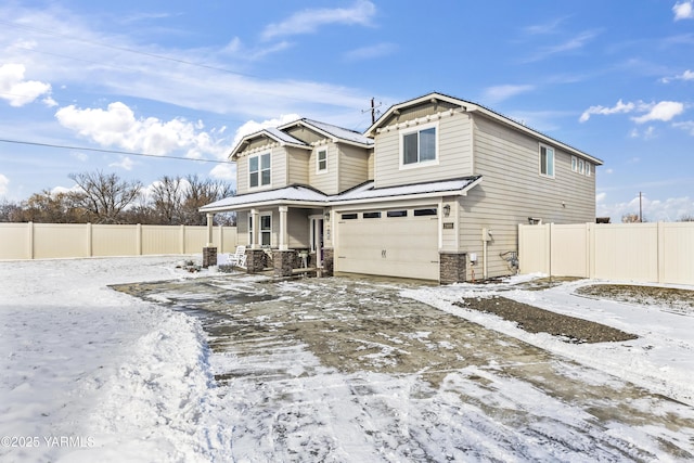 view of front of house with an attached garage, fence, and metal roof