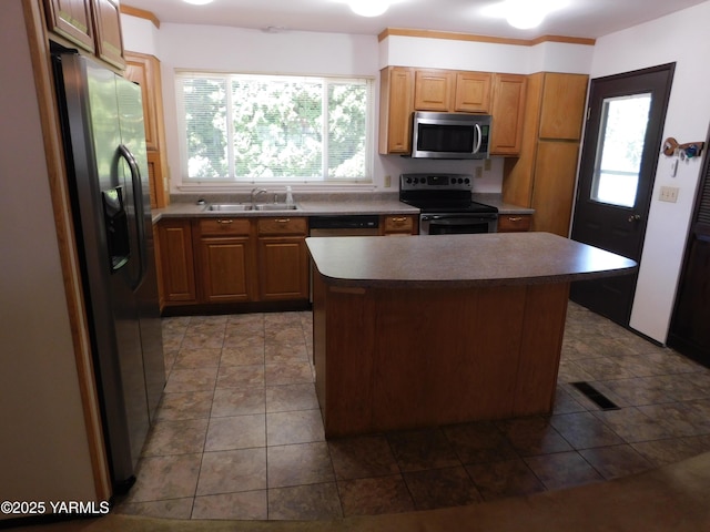 kitchen with a center island, brown cabinets, appliances with stainless steel finishes, a healthy amount of sunlight, and a sink